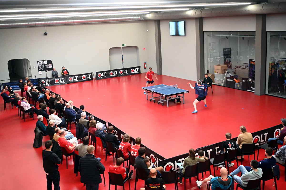 Publiek rond de tafels tijdens een tornooi in de grote zaal van QLT